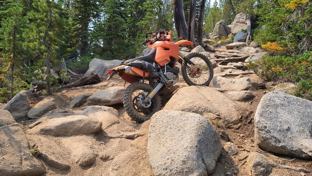 a motorcycle parked amoung large rocks on a steep trail
