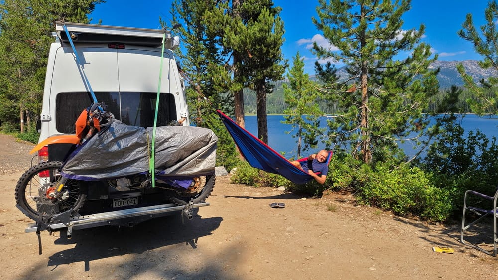 a person in a hammock next to a lake