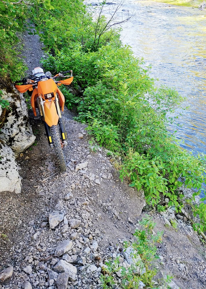 motorcycle parked between a rock and a drop-off