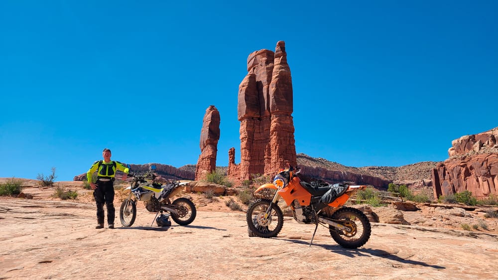 motorycle and rider in front of red rock spires