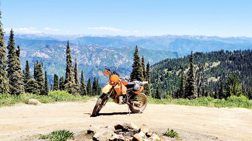 motorcycle paked high on a mountain with a sweeping vista behind