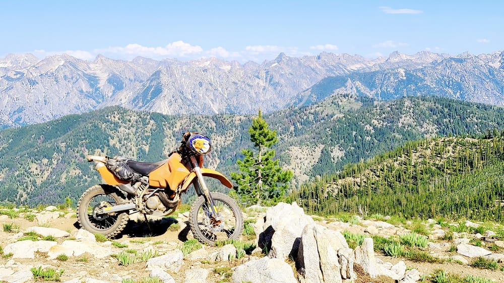 motorcycle parked on a mountain with jagged mountain peaks behind