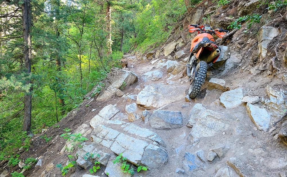motorcycle leaning against a steep rocky hill