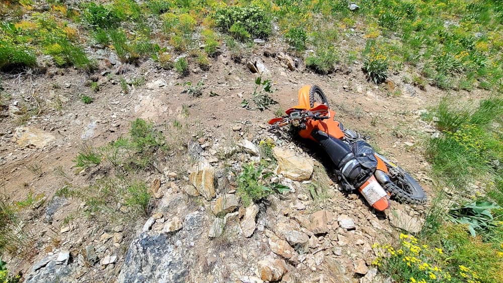 motorcycle laying down on a steep mountain side