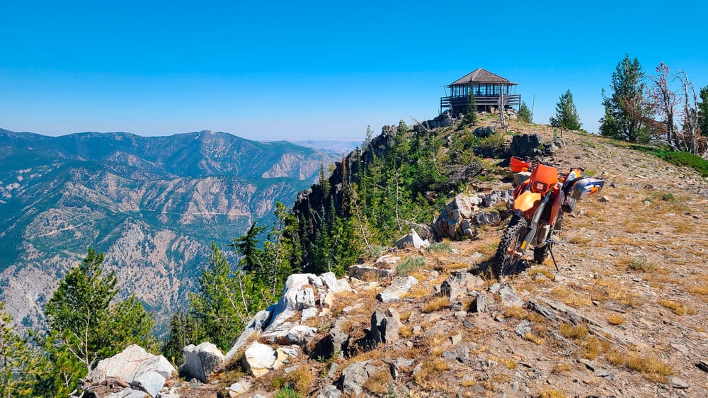 motorcycle parked atop a mountain with fire lookout behind