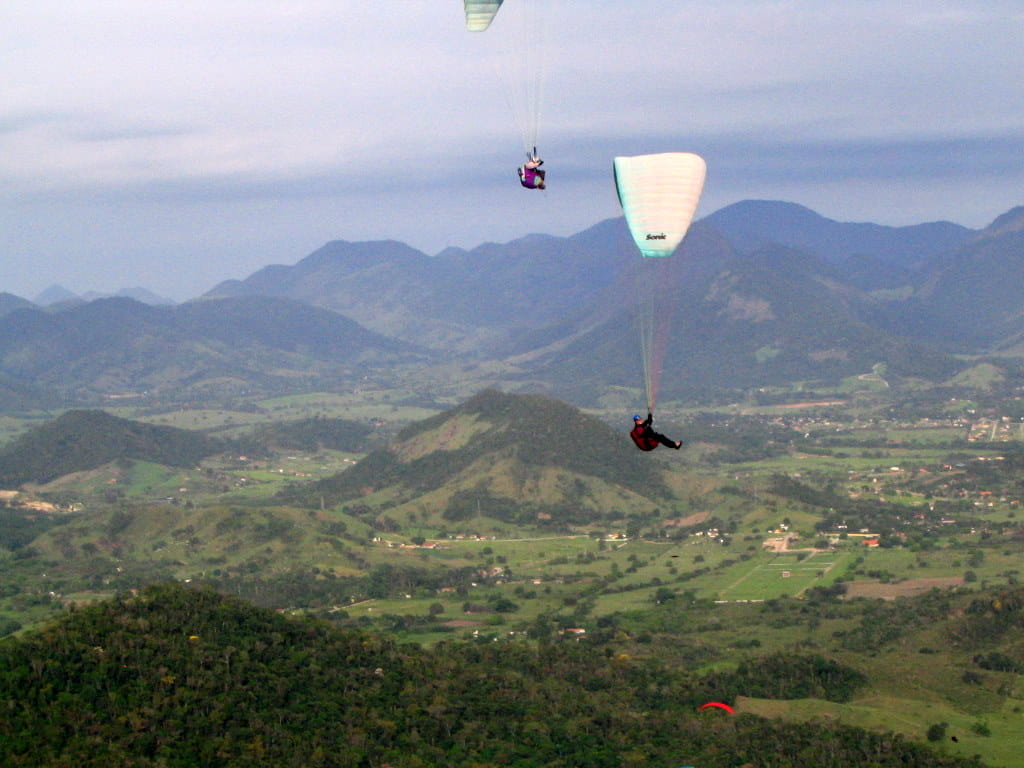 a group of paragliders high above forested hills