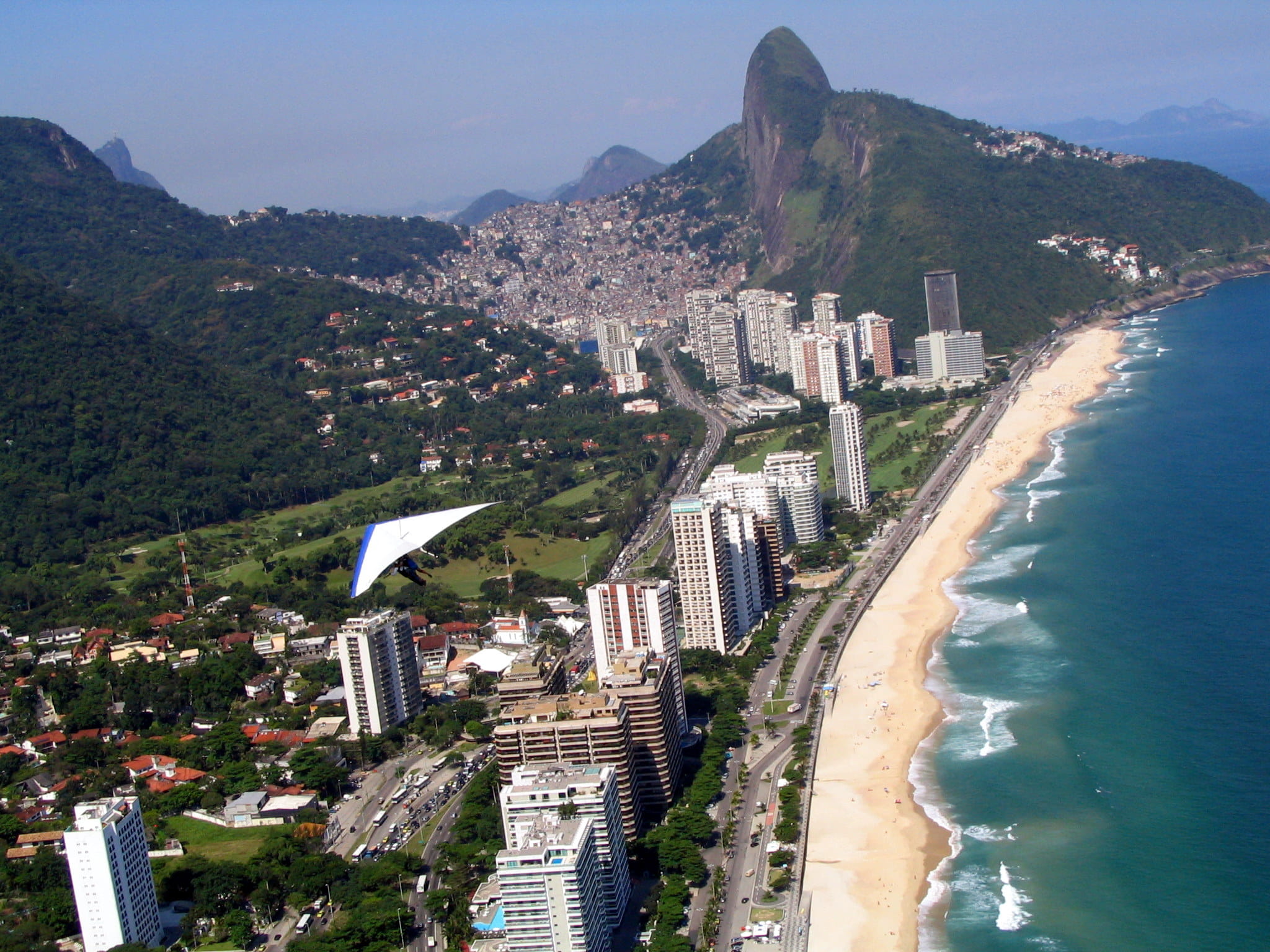 Areal view of a long beach and a hangglider below