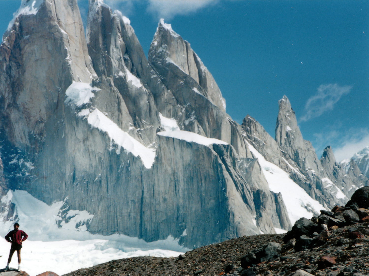 person posing with a sniow covered jagged peaks behind 