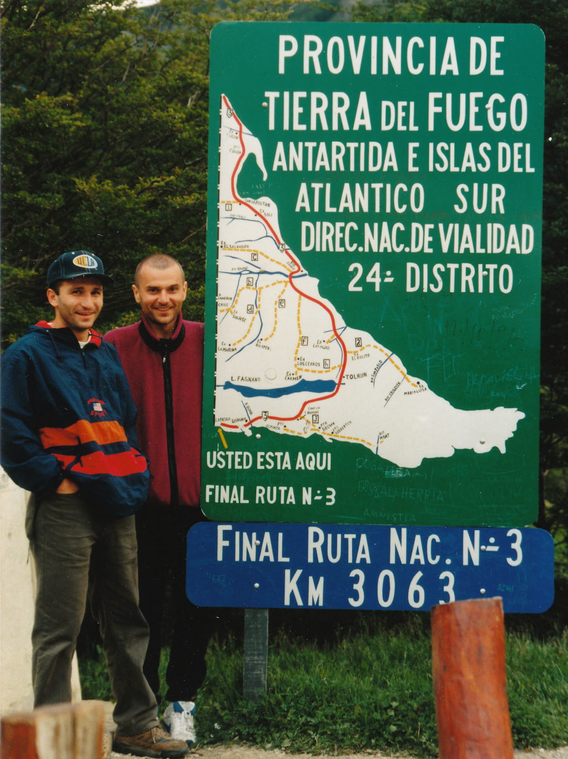 two guys next to a sign fin del mundo 