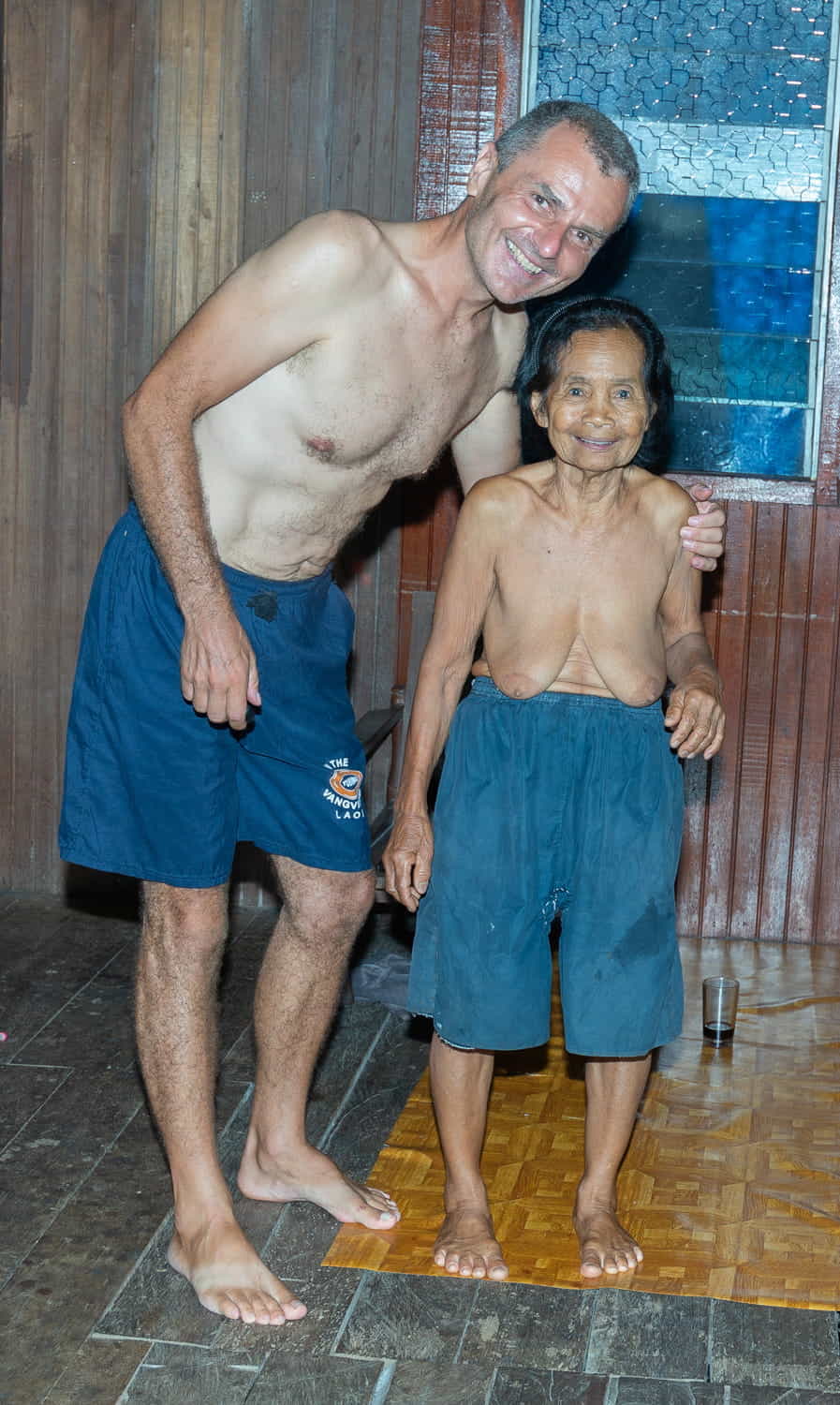 a guy and an olderly topless lady posing together