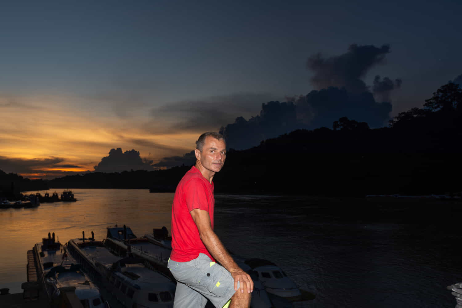 a person above river and several boats ancored at dusk