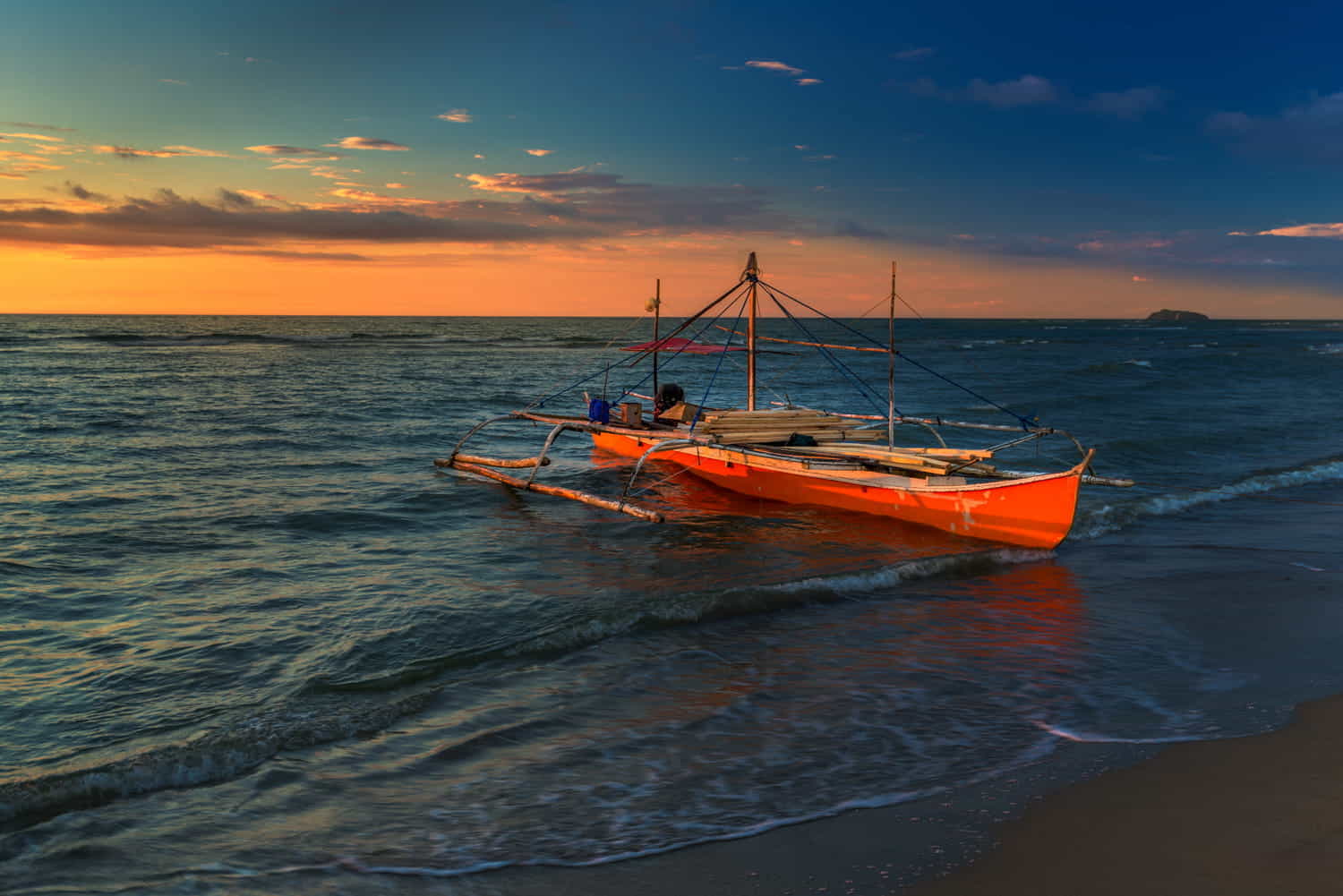 a traditional boat on a beach at sunset