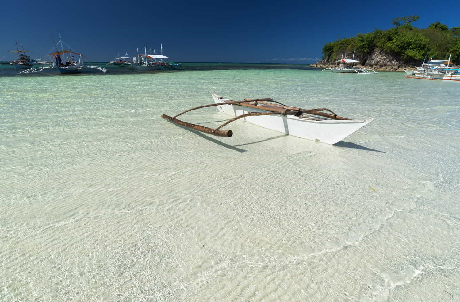 a small boat in shallow waters with white sand at the bottom