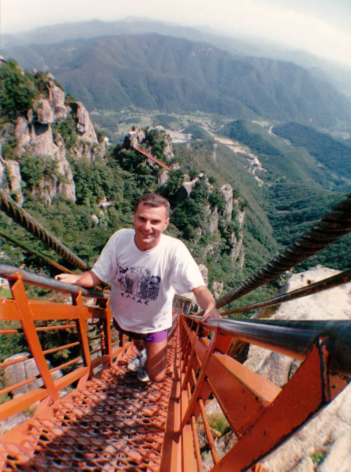 person climbing steep red ladder up a rock