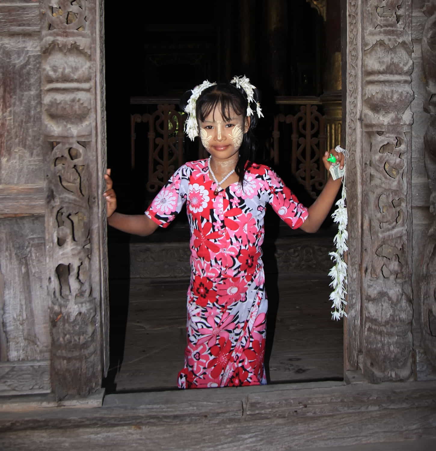 a girl with flowers next to carved doorway