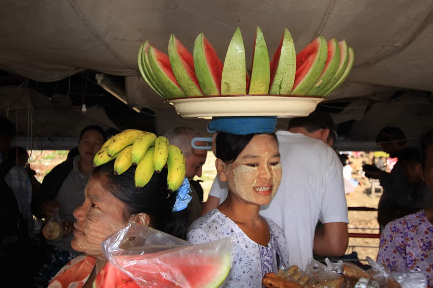 a lady with a tray full of cut fruits atop her head