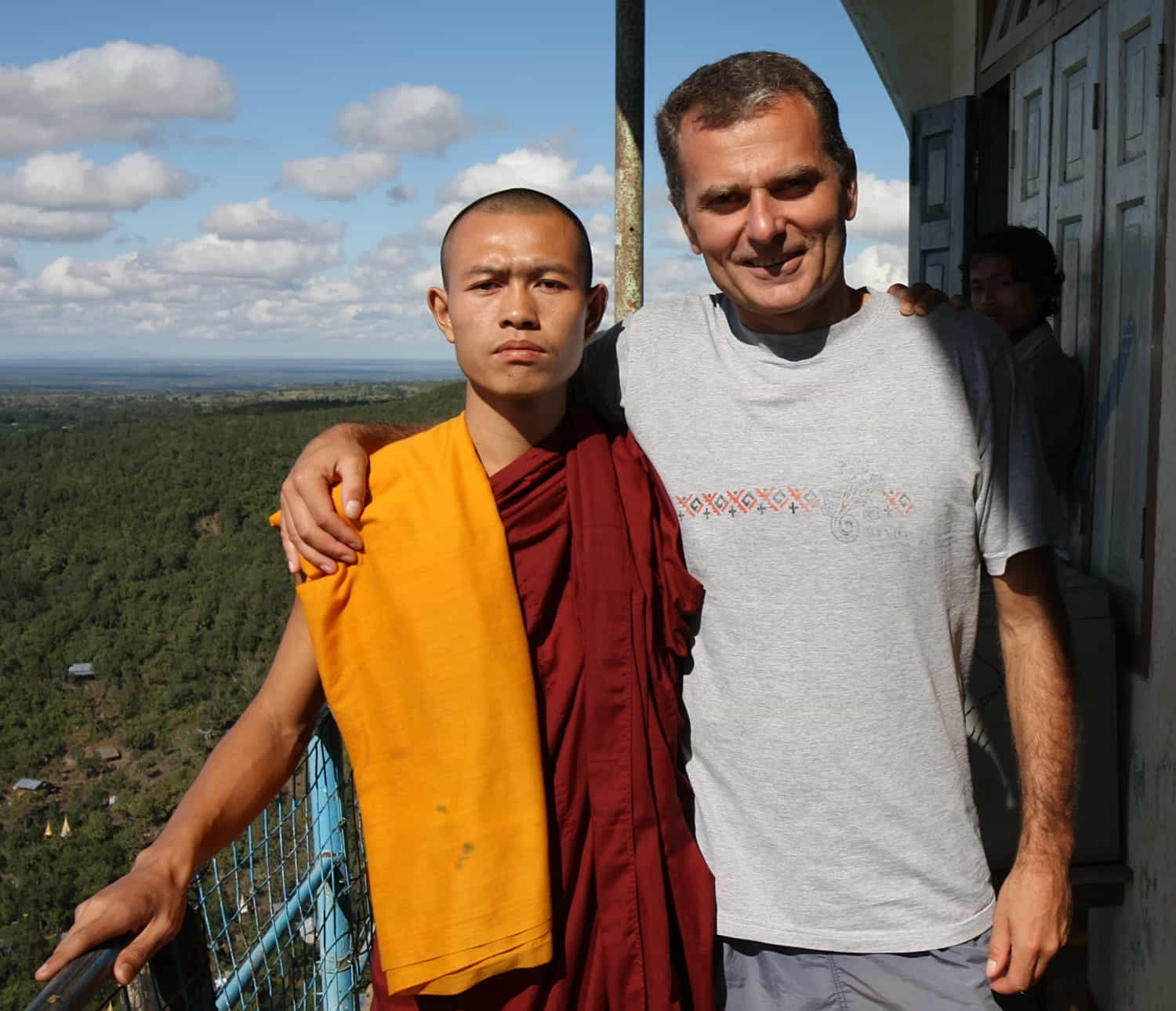 a tourist posing with a monk for a photo