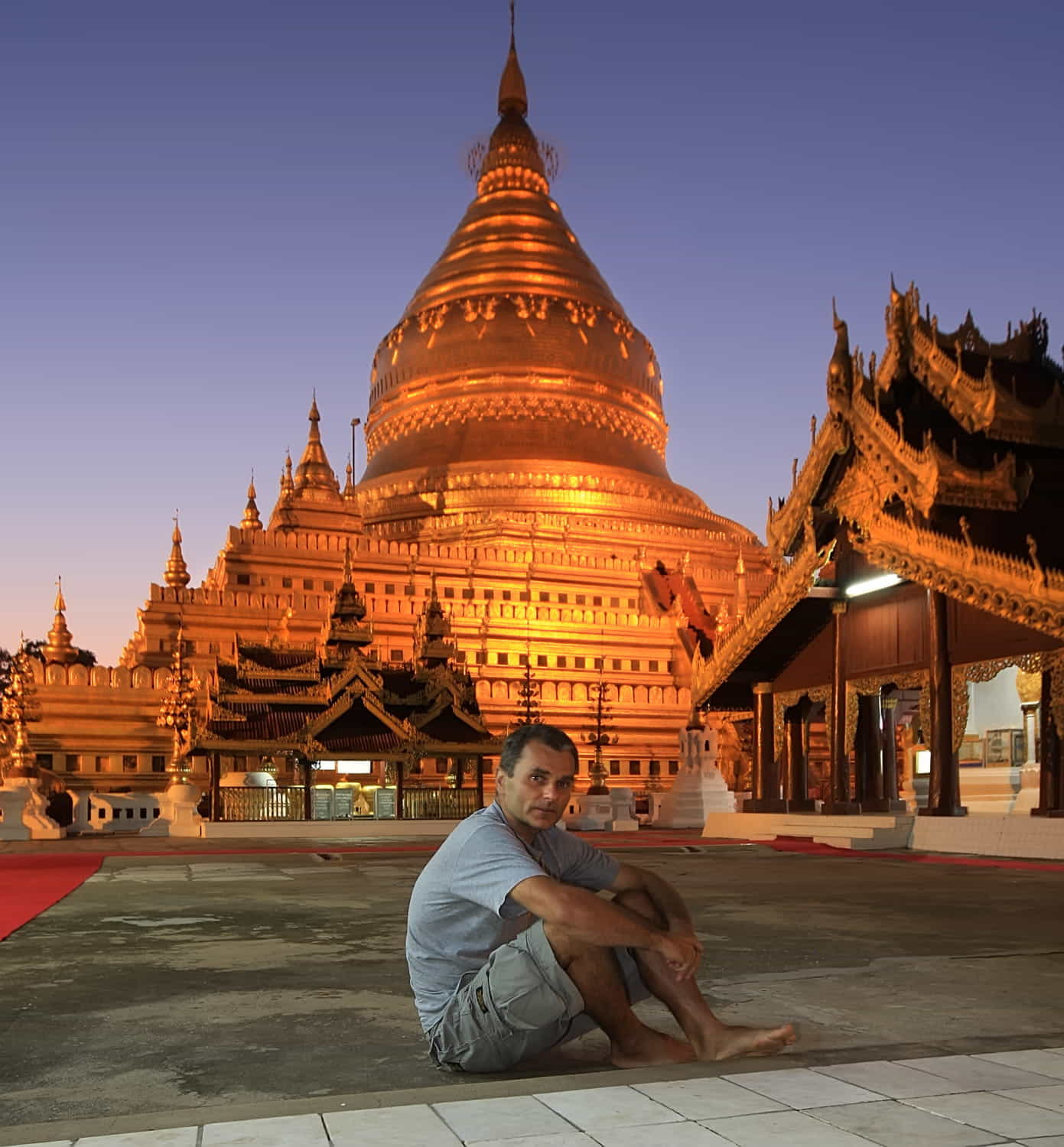 sitting in front of a stupa at dusk