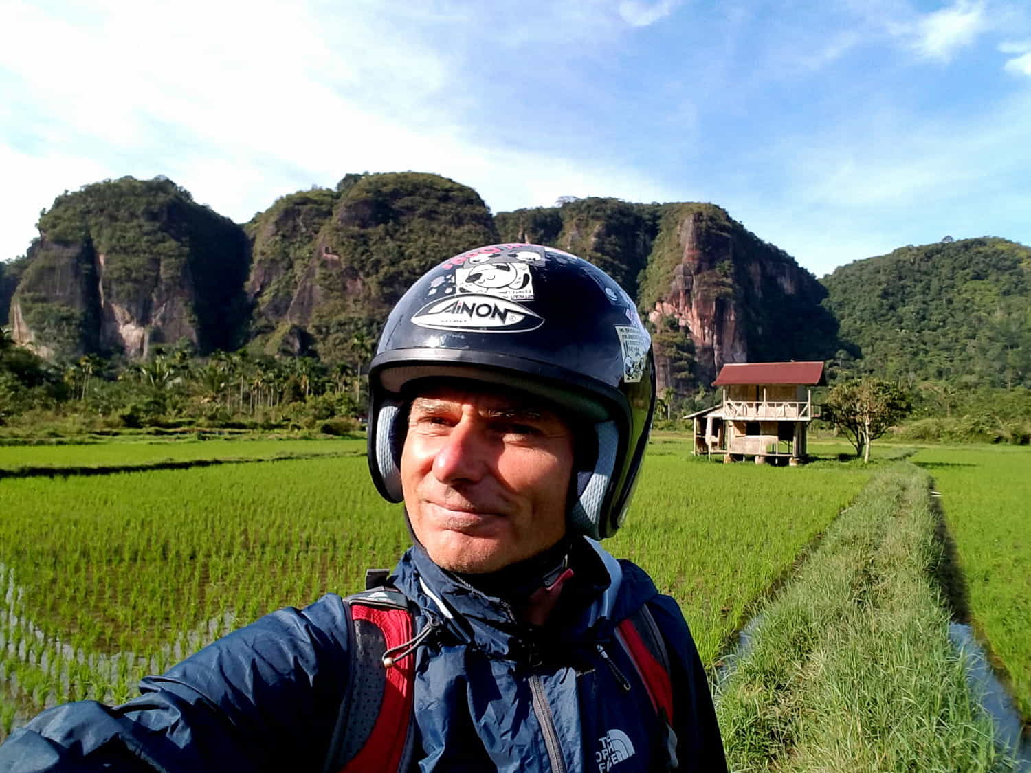 motorcycle rider with rice fields behind 