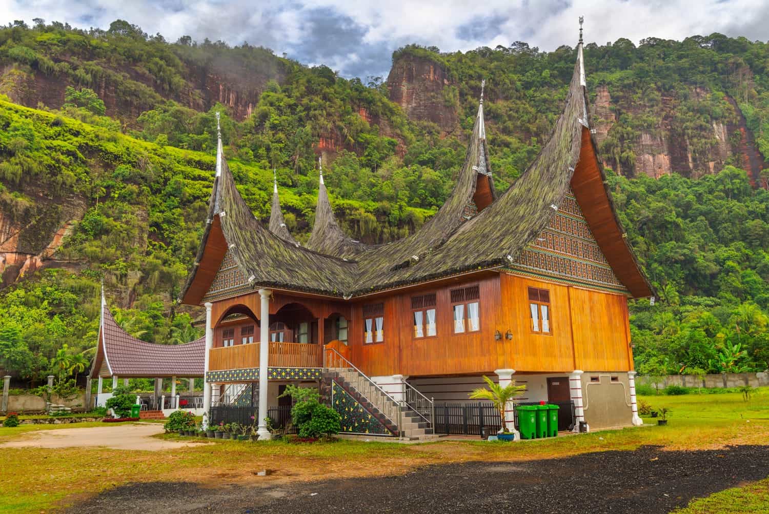 a sumatran house with jungle covered mountain behind 