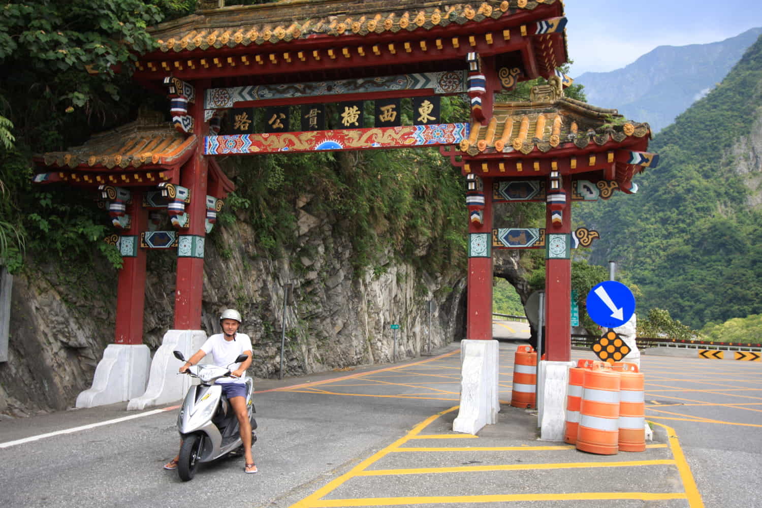 rider on a scooter under a gate leading into a canyon