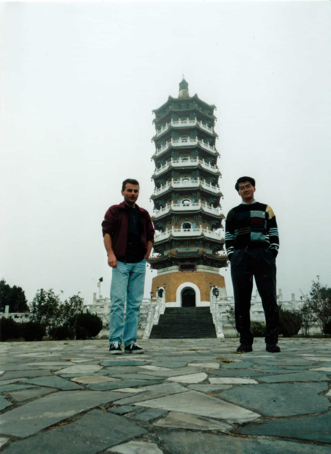 two guys posing in front of a tall pagoda