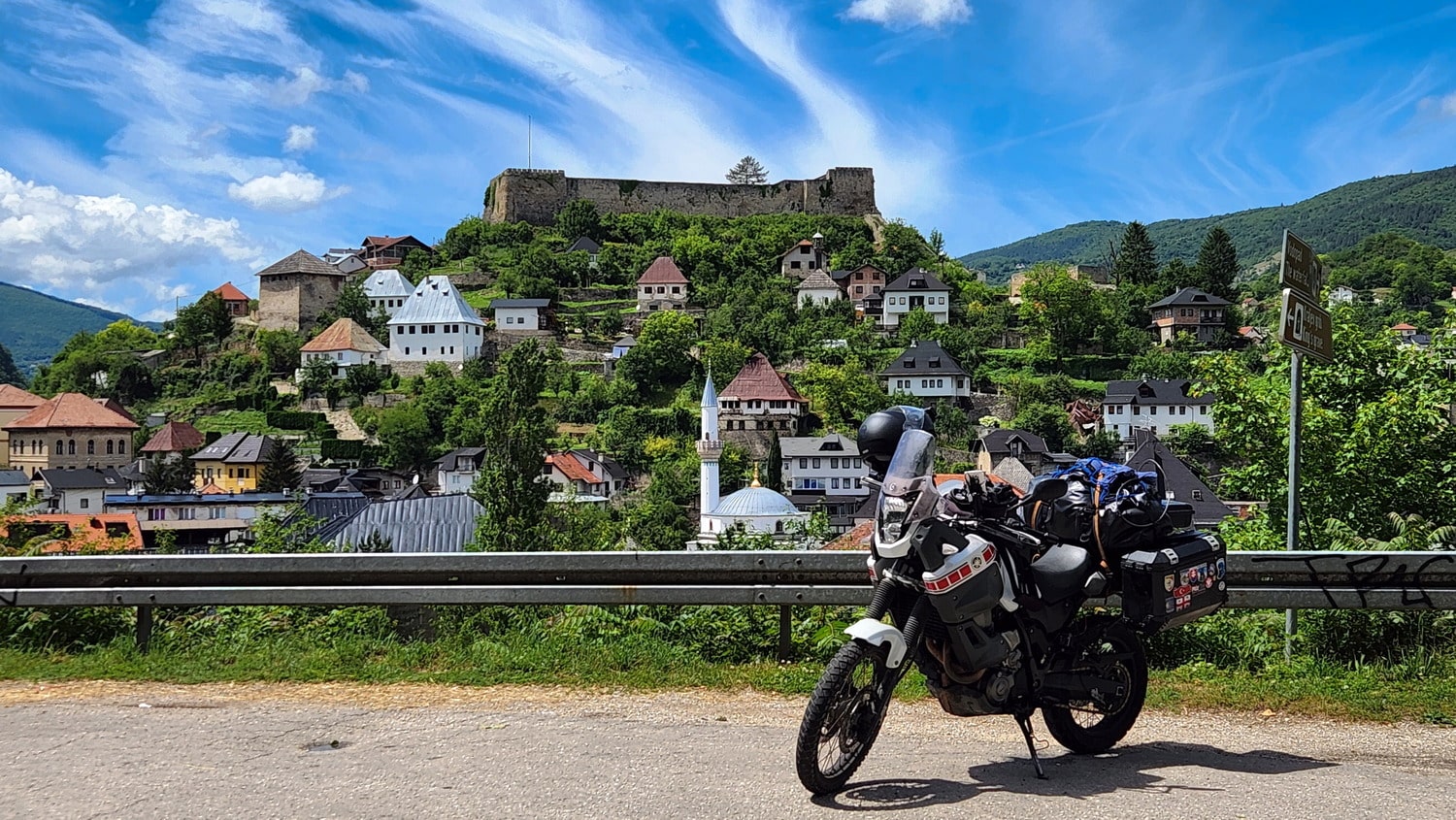 motorcycle and town on a steep hill with an old fortress atop