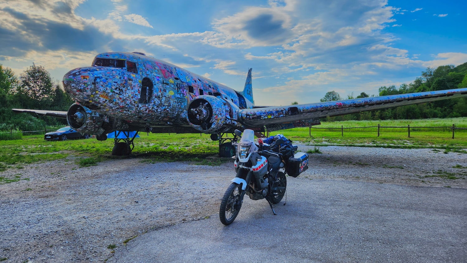 motorcycle next to an old airplane covered with stickers 