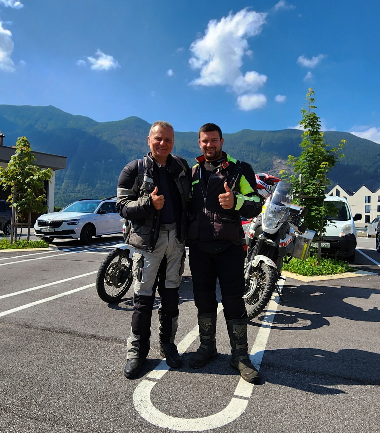 two motorcycle riders with their bikes behind