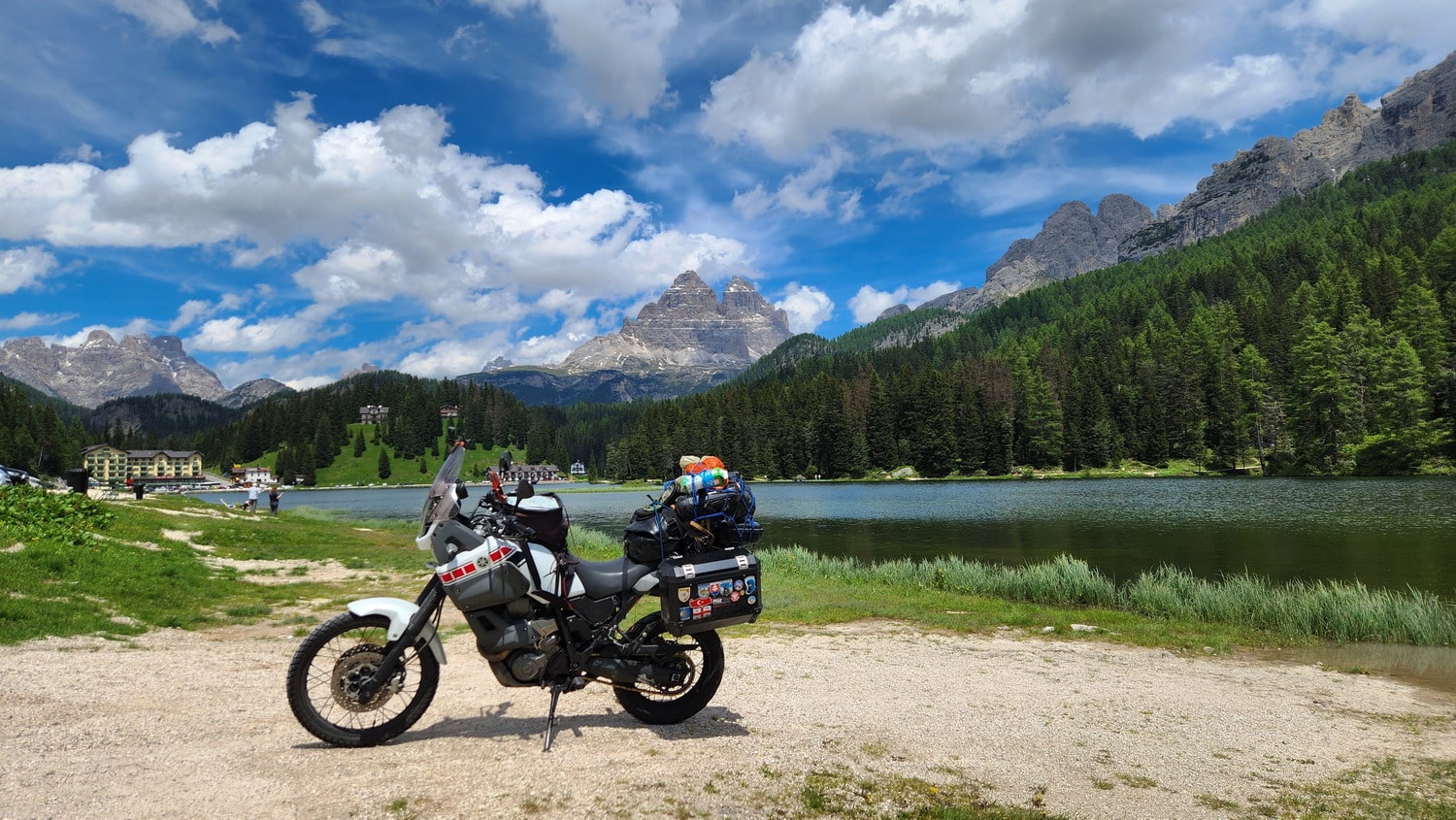 motorcycles parked next to a lake with mountains behind