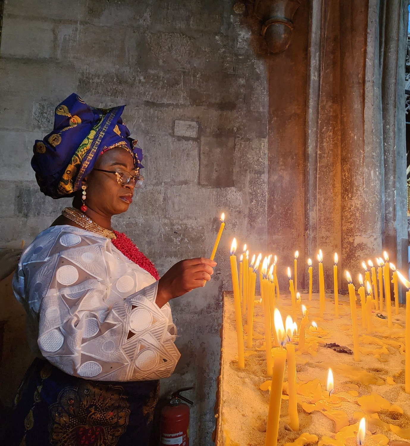 a lady lighting up candle in a cathedral