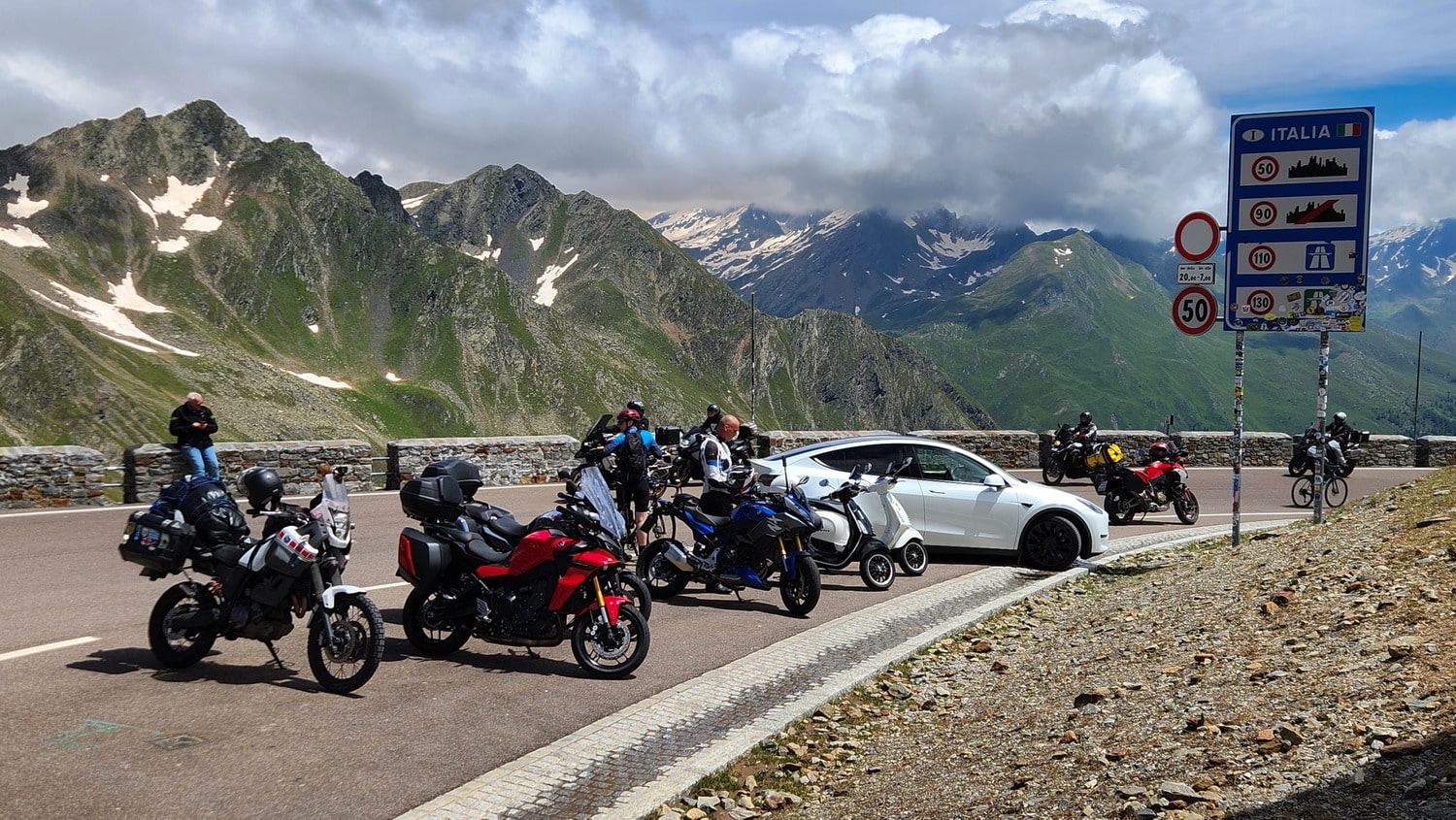 many motorcycles parked on a road high up in the mountains