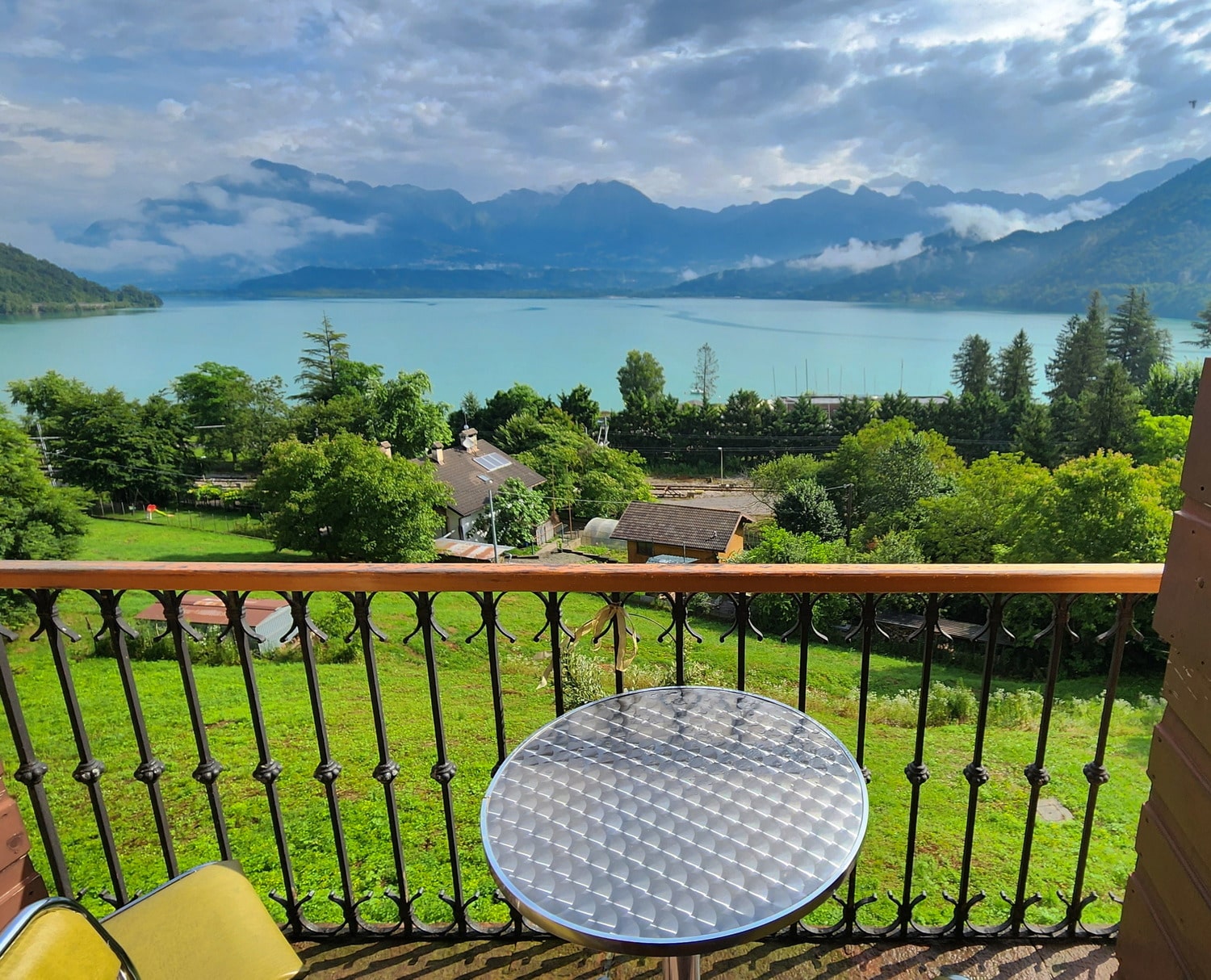 chair and table on a balcony overlooking grass and lake