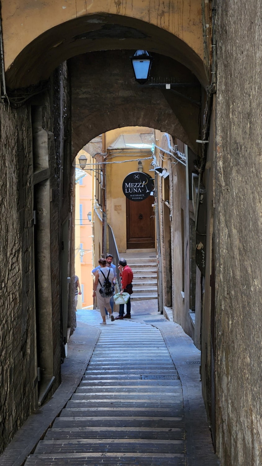 people standing and chatting at the end of a narrow alley