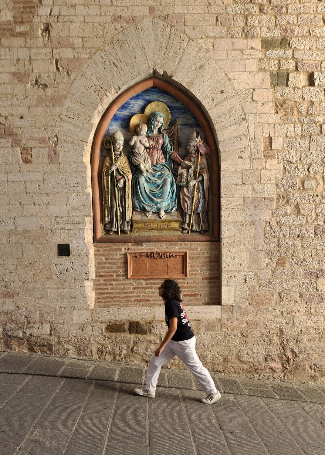 person walking next to a religious motiv on a wall