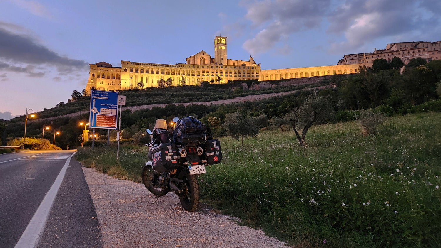 a motorcycle and huge illuminated building at dusk