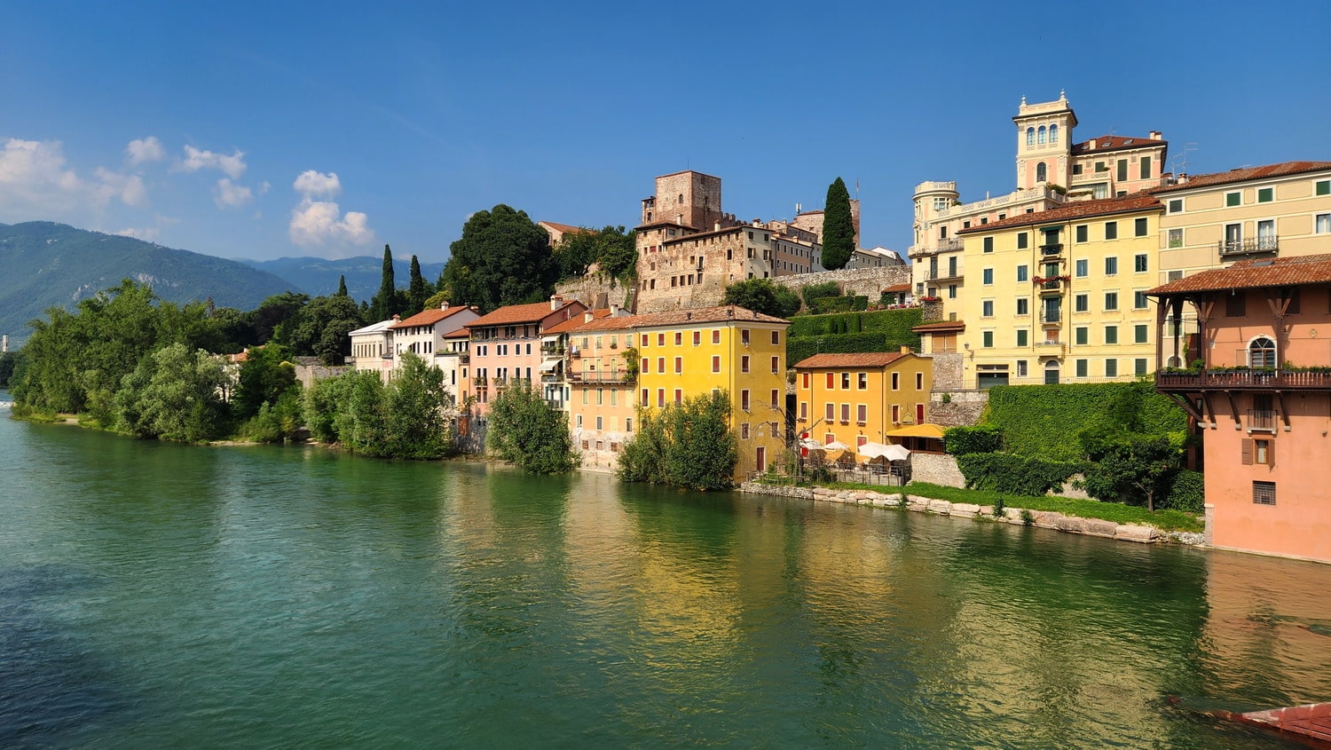 view of a green river and colorful buildings on the other side