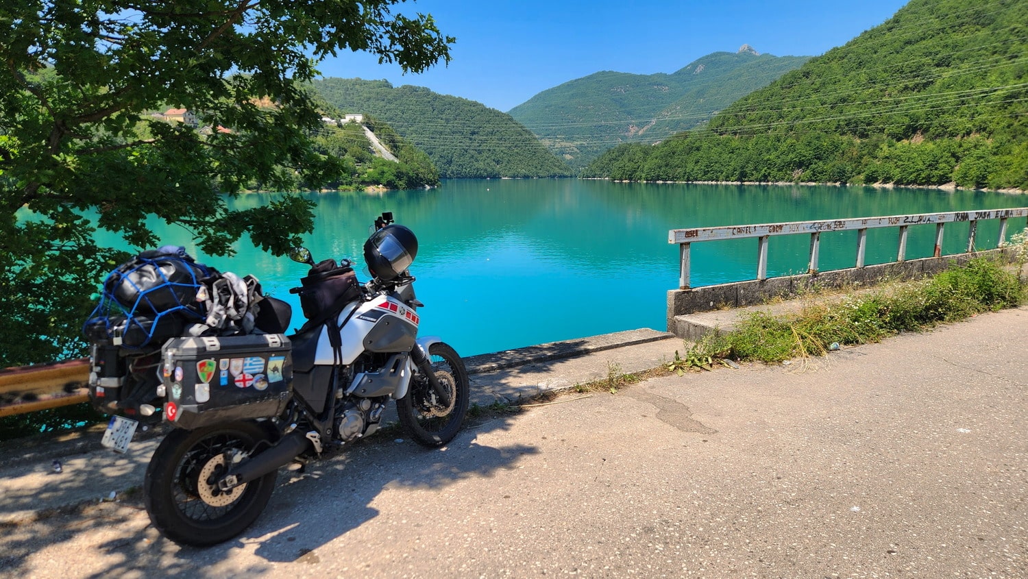 motorcycle parked next to a blue-green lake