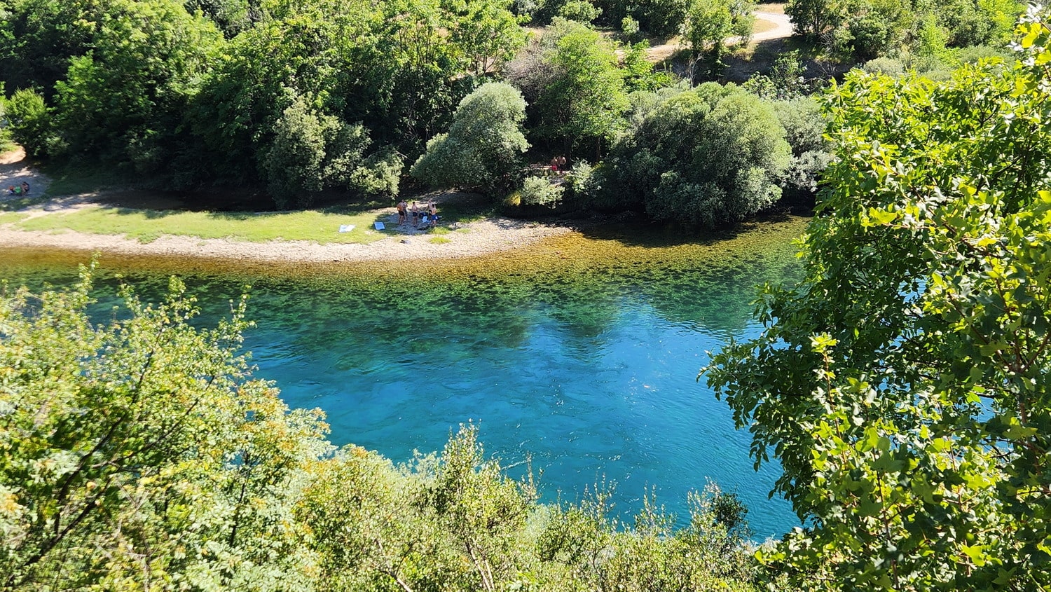 people next to a crystal clear river