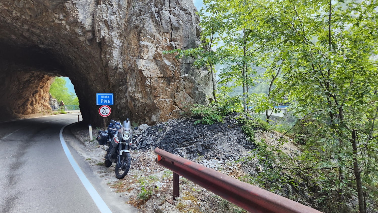 motorcycle parked next to a tunnel at the edge of a canyon