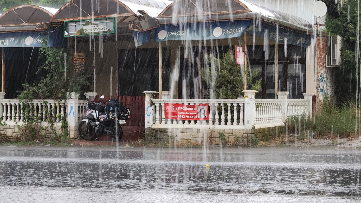 motorcycle under a cover in heaevy downpour