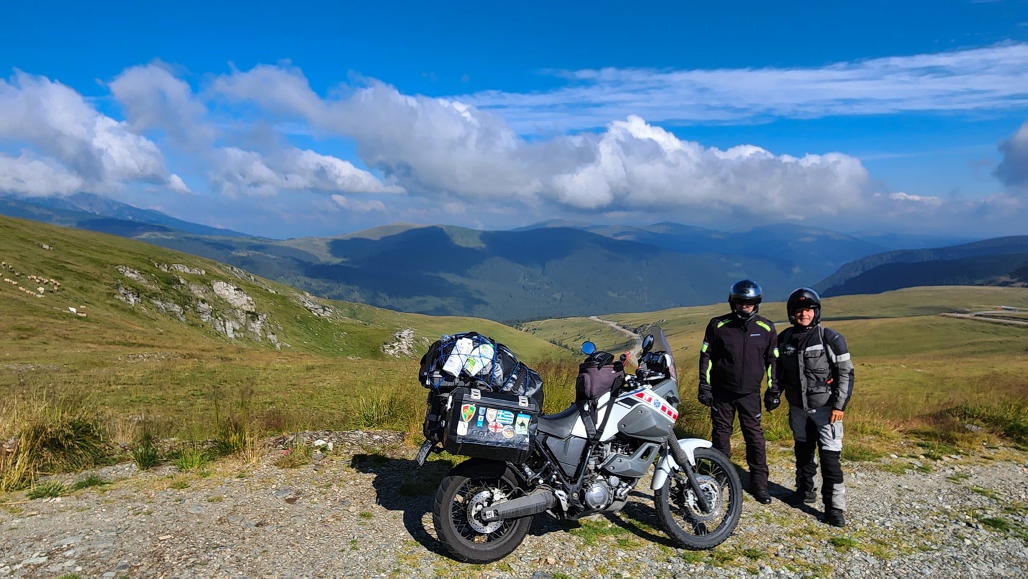 two riders with motorcycles atop a mountain