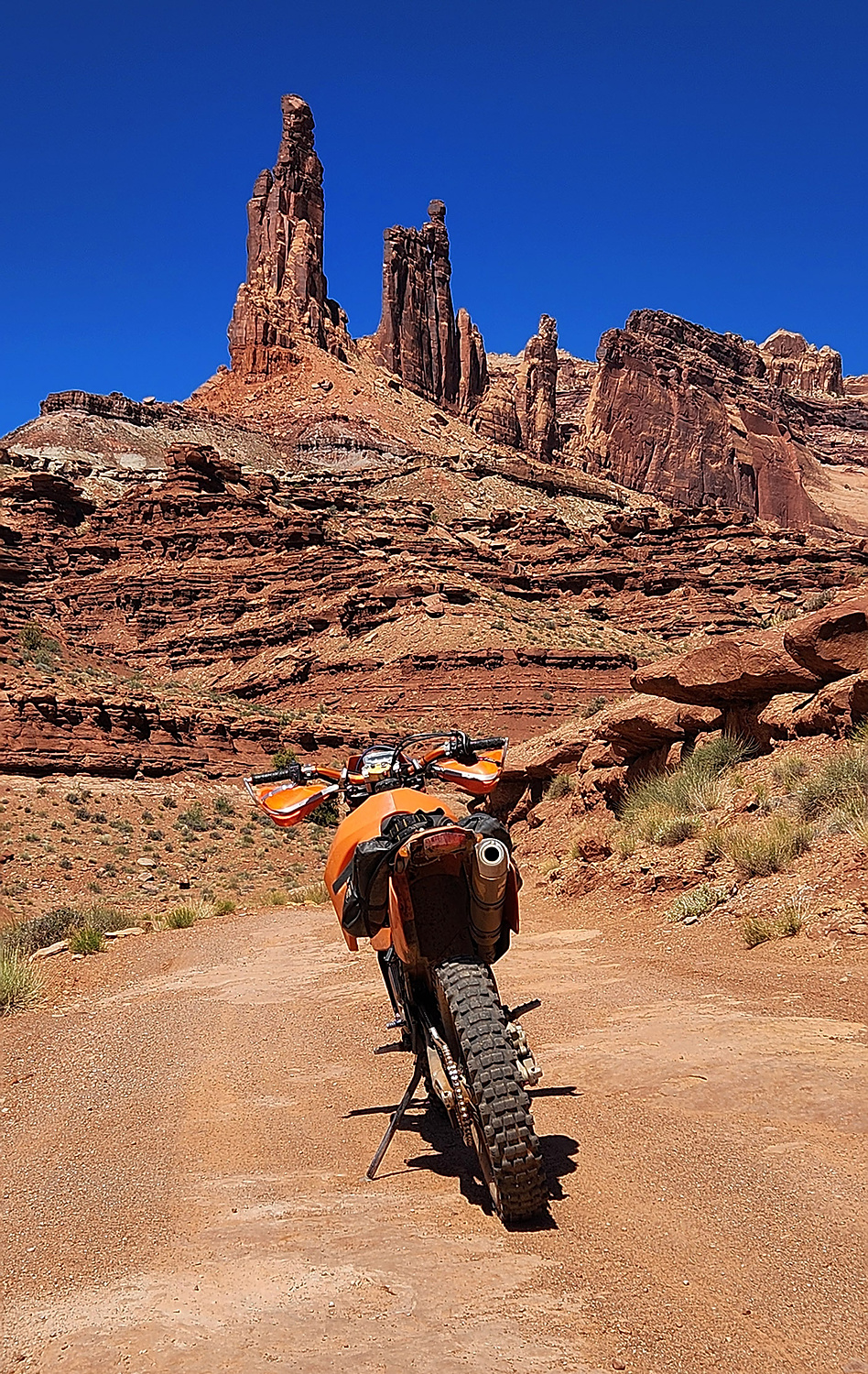 motorcycle parked on a dirt trail with rock spires behind