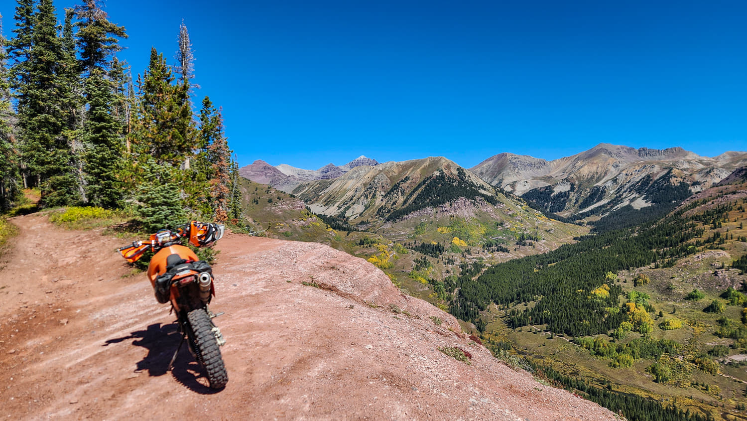 a motorcycle at a viewpoint overlooking valley and peaks in the distance