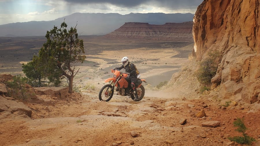 rider clibing out of a canyon on a rough dirt track