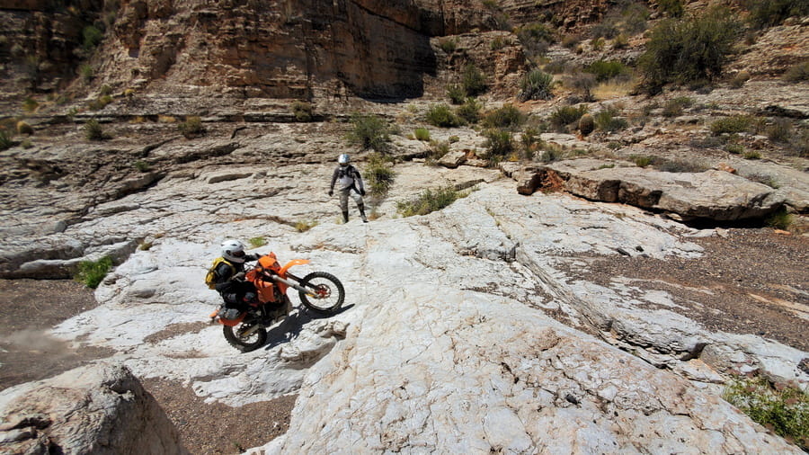 rider clibing out of a dry canyon wash