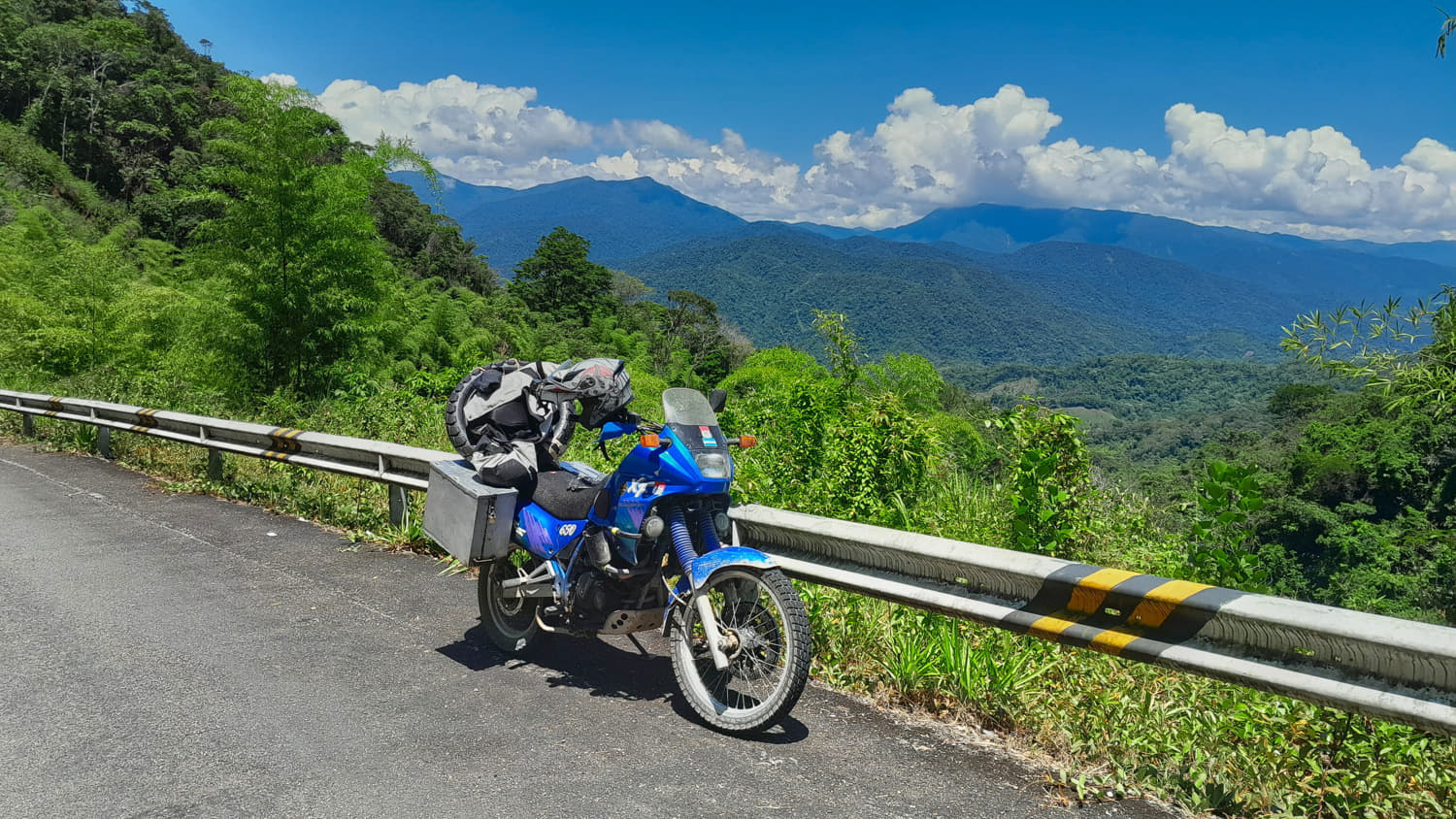 motorcycle parked with jungle covered rolling hills behind