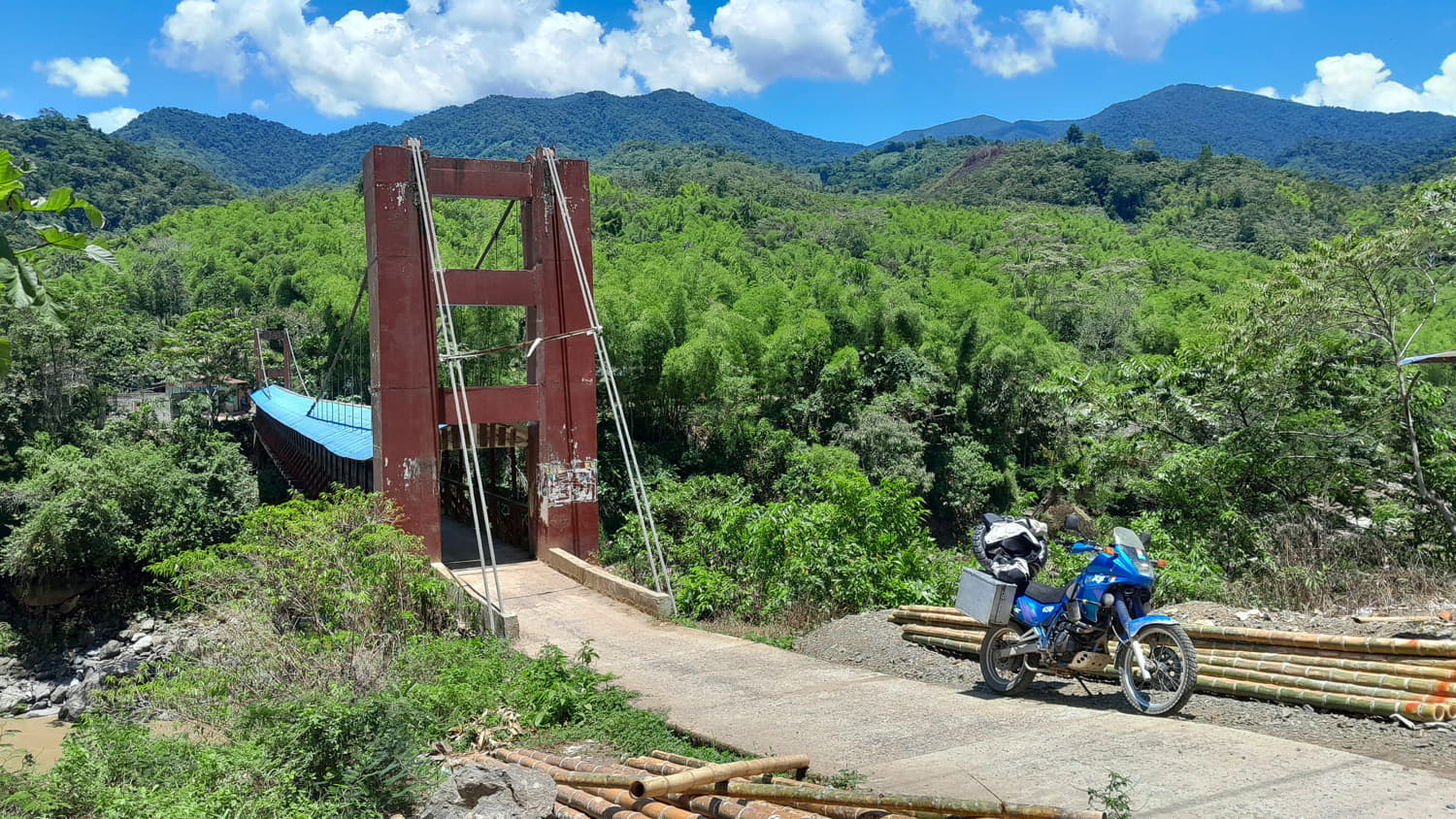 motorcycle parked in front of a covered suspension bridge