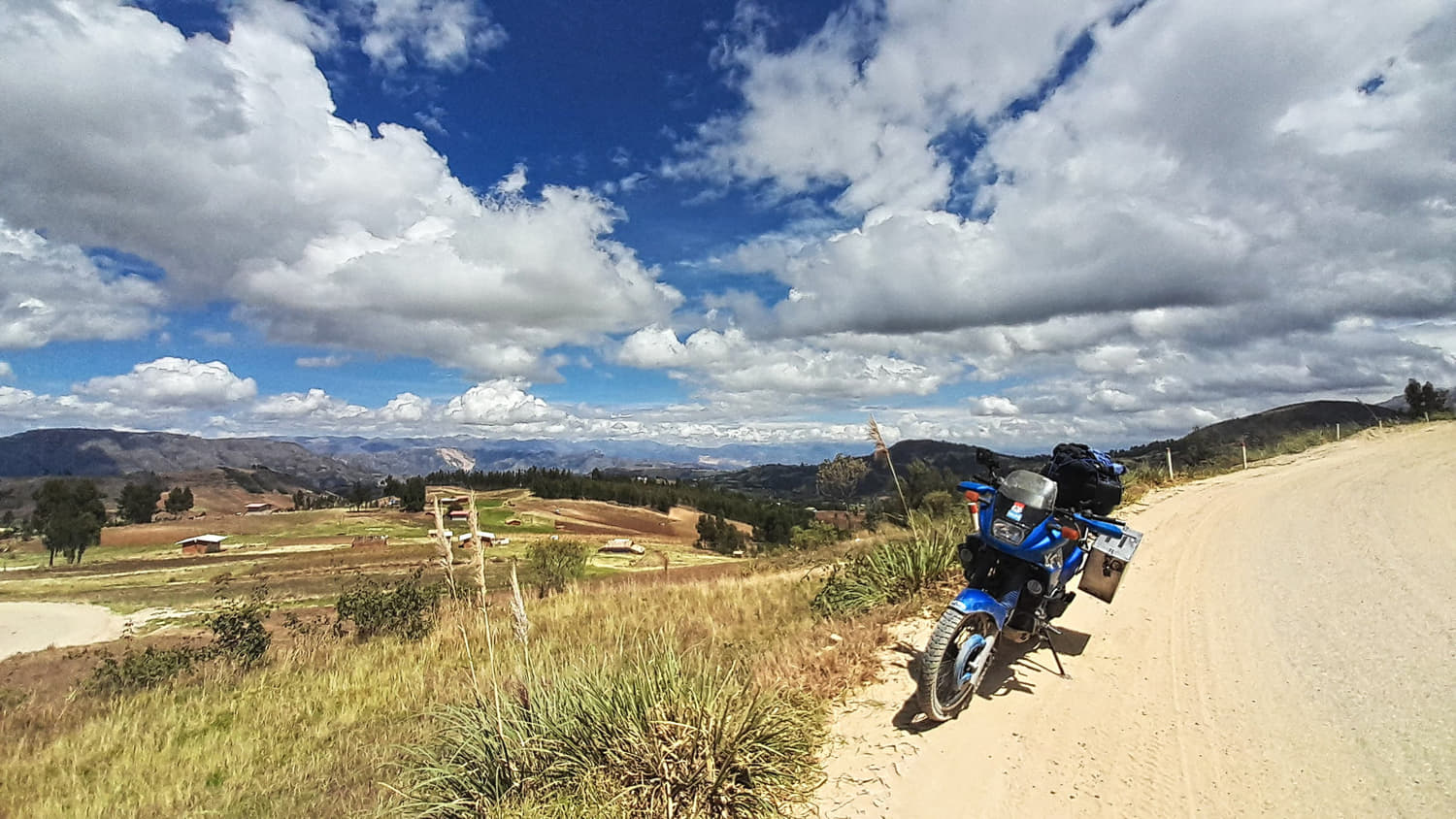 motorcycle on a dirt road with fluffy clouds behind