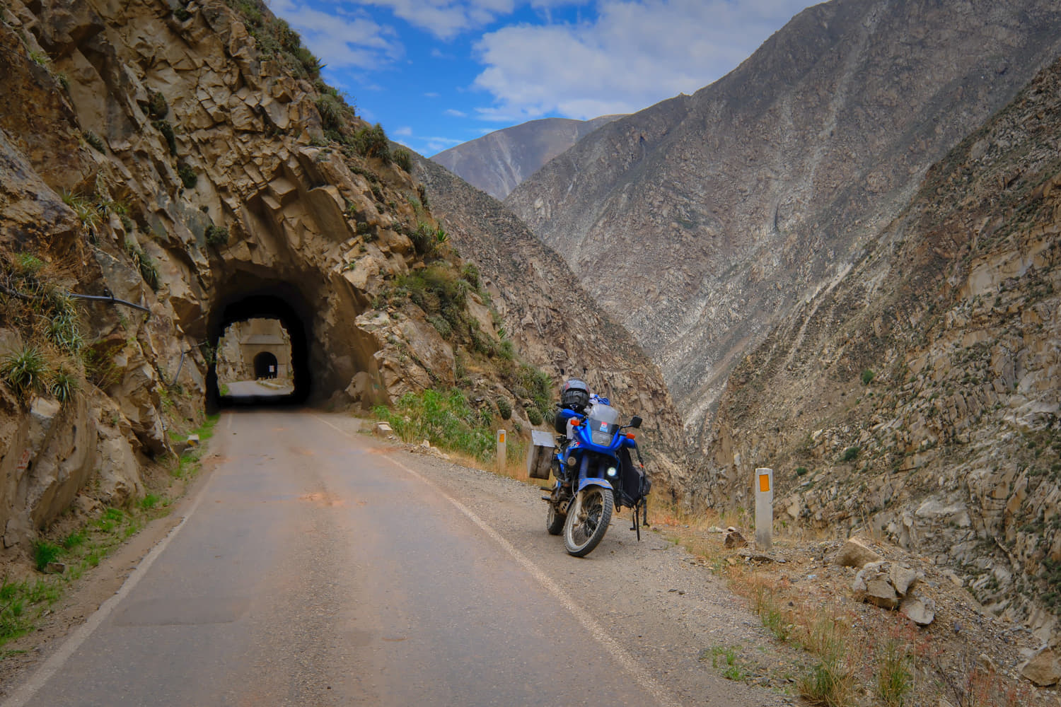 motorcycle parked on a road next to a tunnel